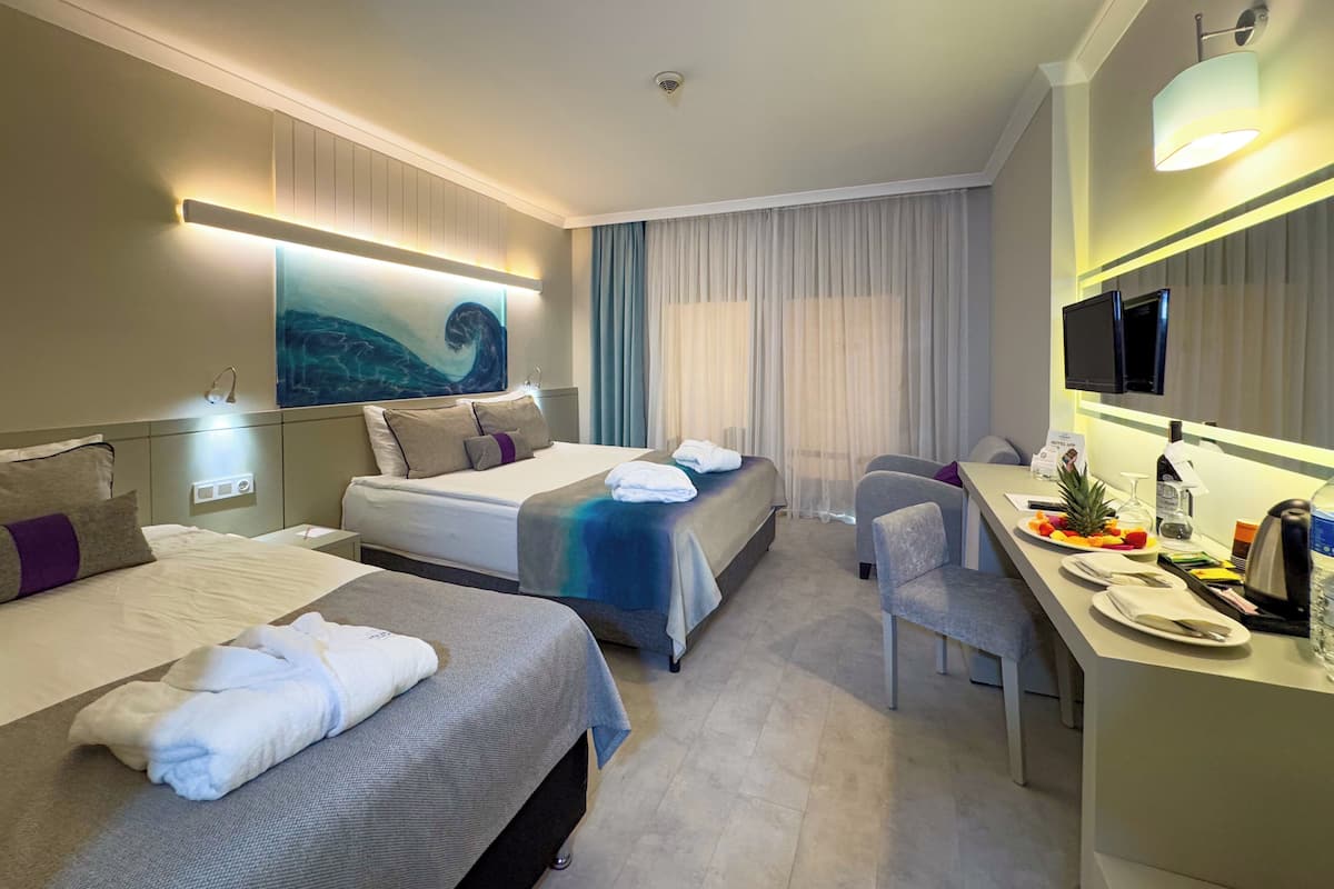 Une chambre d’hôtel avec deux lits, un bureau avec une chaise, une télévision et un tableau au mur.