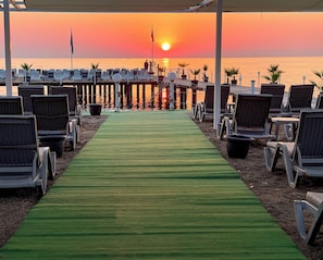 A beachside lounge area with rows of chairs and a green carpet leading to the water. - Catamaran Resort Hotel (Kemer)