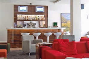A bar area with a wooden backdrop, bar stools, and a seating area with red and grey sofas. - Anemon Gonlu Ferah Bursa (Bursa)