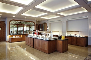 A spacious hotel lobby with a central island, wooden cabinetry, and a large arched window. - Anemon Gonlu Ferah Bursa (Bursa)