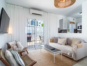 Ein modernes Wohnzimmer mit einer Couch, einem Couchtisch, einem Fernseher und einem Balkon mit Blick.