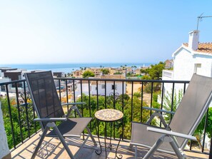 A balcony with two chairs and a small table, overlooking a coastal town with buildings and the sea. - Casa Lovisa Private Pool by Casasol by Interhome (Nerja)