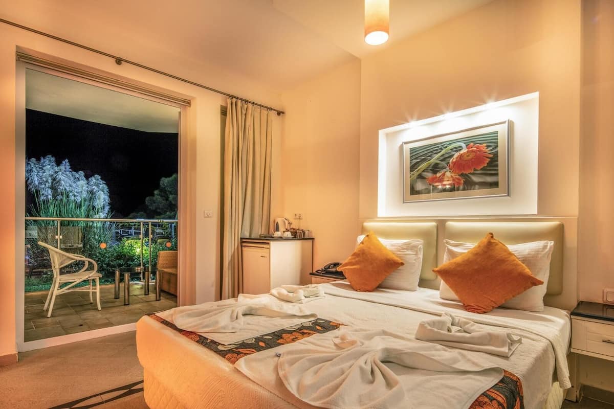 Ein Hotelzimmer mit Bett, Nachttisch und Blick auf den Balkon.