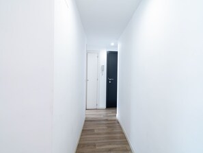 A narrow hallway with a wooden floor, white walls, and two doors, one white and one dark. - Sirena Deluxe Torrecilla by Casasol by Interhome (Nerja)