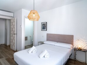 Ein Hotelzimmer mit Bett, Nachttisch mit Lampe, einer Tür und einem an der Wand hängenden Bild.
