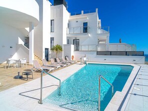 A swimming pool with sun loungers and a white building with balconies. - Terrazas de Ladera A2 Luxury by Casasol by Interhome (Nerja)