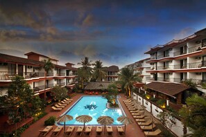 A hotel with a swimming pool, multiple balconies, and palm trees. - Pride Sun Village Resort (Arpora)