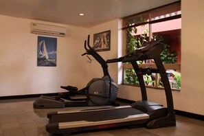 A gym with a treadmill, stationary bike, and a wall-mounted air conditioner. - Pride Sun Village Resort (Arpora)