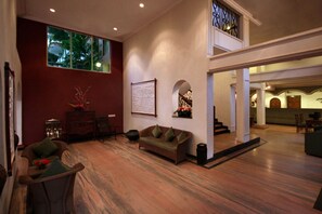 A spacious living area with a large window, a sofa, a coffee table, and a fireplace. - Pride Sun Village Resort (Arpora)