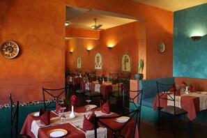 Un restaurante con varias mesas, sillas y un ventilador de techo.
