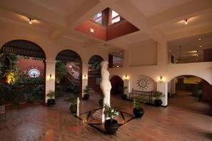 Un vestíbulo espacioso con techo alto, arcos y una escultura central.