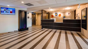 A reception area with a modern design, a reception desk, a digital display, and a patterned floor. - Best Western Plus Lower South End (Charlotte)