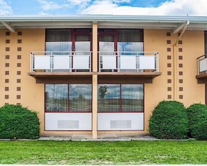 Un bâtiment à deux étages doté d’un balcon central, de grandes fenêtres et d’un toit plat.