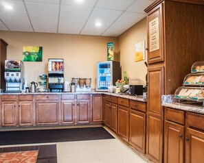 A hotel kitchen with a coffee machine, a refrigerator, and a buffet counter. - Quality Inn Airport Buffalo (Buffalo)