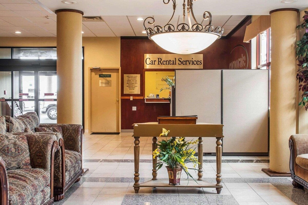 A reception area with a 'Car Rental Services' sign, a reception desk, and a seating area with patterned sofas.