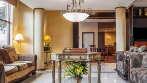 Un vestíbulo de hotel con una lámpara de araña clásica, un sofá, una mesa con un jarrón de flores y un televisor al fondo.