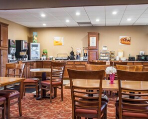 A hotel dining area with wooden tables and chairs, a coffee machine, and a menu board. - Quality Inn Airport Buffalo (Buffalo)