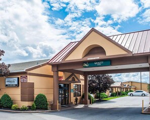 A Quality Inn with a covered entrance, a sign for a corporate rental car dealership, and a clear sky. - Quality Inn Airport Buffalo (Buffalo)