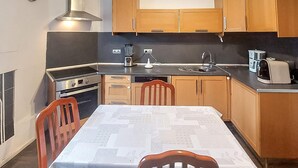 Una cocina funcional con armarios de madera, estufa a gas, pileta y mesa de comedor con sillas.