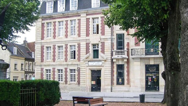 Un edificio histórico con fachada simétrica, múltiples ventanas y una entrada central.