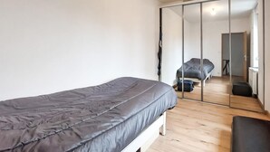Un dormitorio con cama, armario y espejo que refleja una cama y una silla.