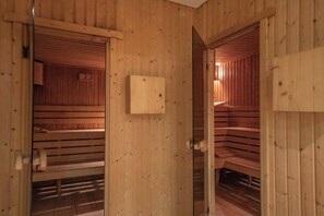 A wooden sauna room with benches and a wooden door. - Grifid Hotel Bolero (Varna)