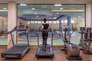 Une salle de sport équipée de tapis de course, d’un vélo elliptique et d’un vélo d’appartement.