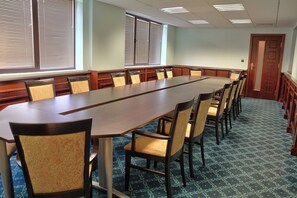 A conference room with a long table and chairs, large windows with blinds, and a patterned carpet. - Grifid Hotel Bolero (Varna)
