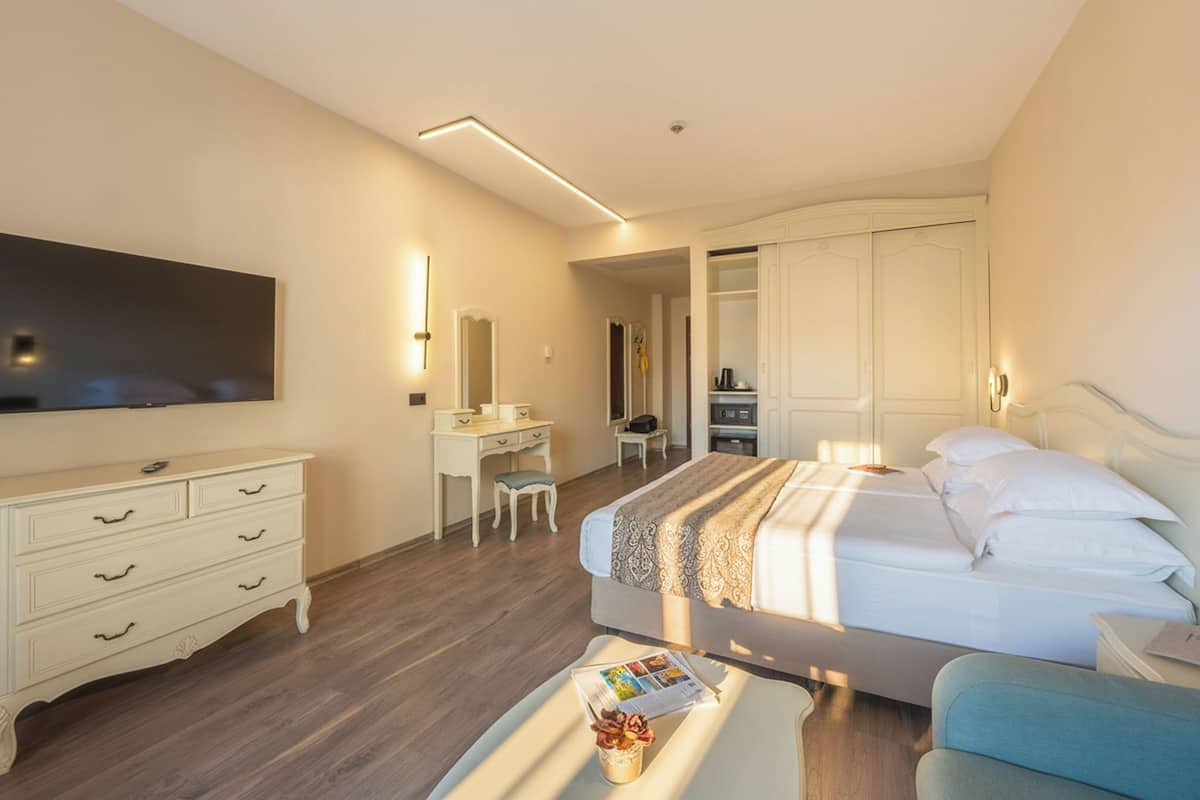 Ein Hotelzimmer mit Bett, Schreibtisch, Stuhl, Fernseher und Kleiderschrank.