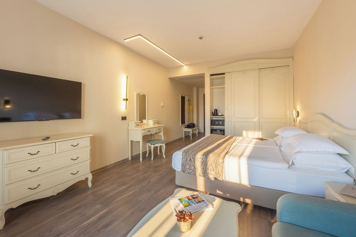 Una habitación de hotel con cama, escritorio, silla, televisor y armario.