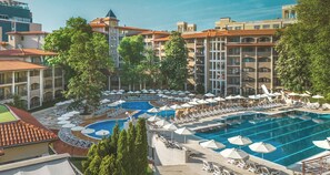 A hotel with a large pool area, multiple lounge chairs, and umbrellas. - Grifid Hotel Bolero (Varna)