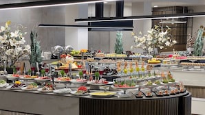 A buffet with various food items and drinks, arranged on a counter with plates and cutlery. - Grifid Hotel Bolero (Varna)