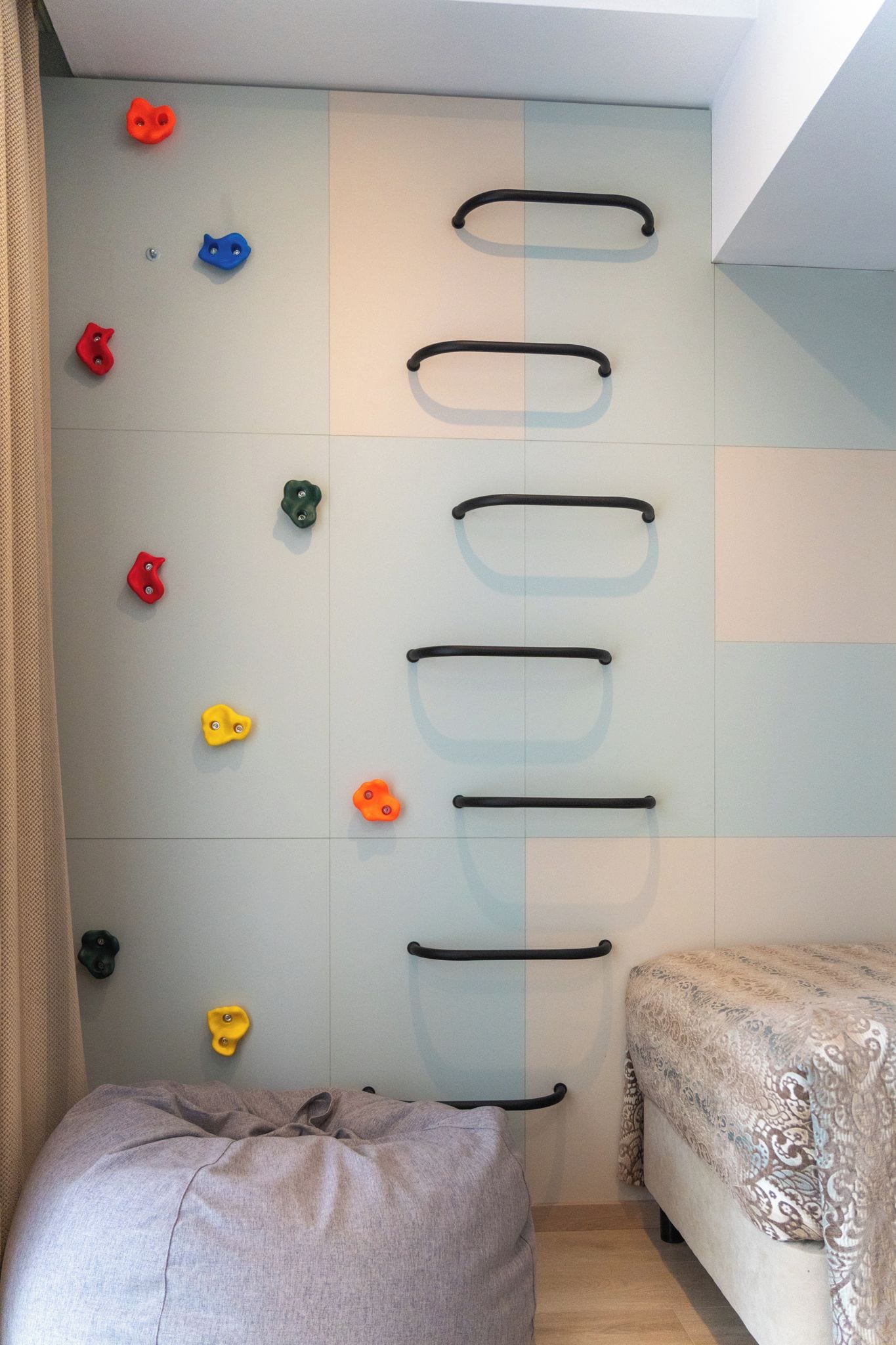 A room with a climbing wall, a bed, and a bean bag.