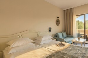 A hotel room with a large bed, a sofa, a small table, and a view of the outdoors. - Grifid Hotel Bolero (Varna)