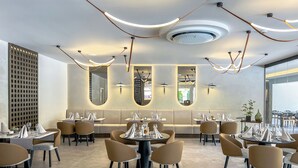 Un interior de restaurante moderno con mesas redondas, sillas color beige y una zona central con un banco acolchado.