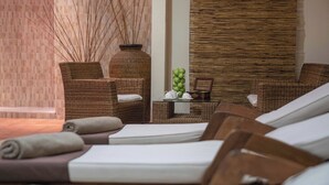 Un área de spa con mobiliario de mimbre, una mesa con manzanas y una tetera, y una pared con un diseño texturizado.