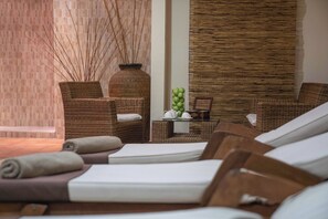 Un área de spa con mobiliario de mimbre, una mesa con manzanas y una tetera, y una pared con un diseño texturizado.