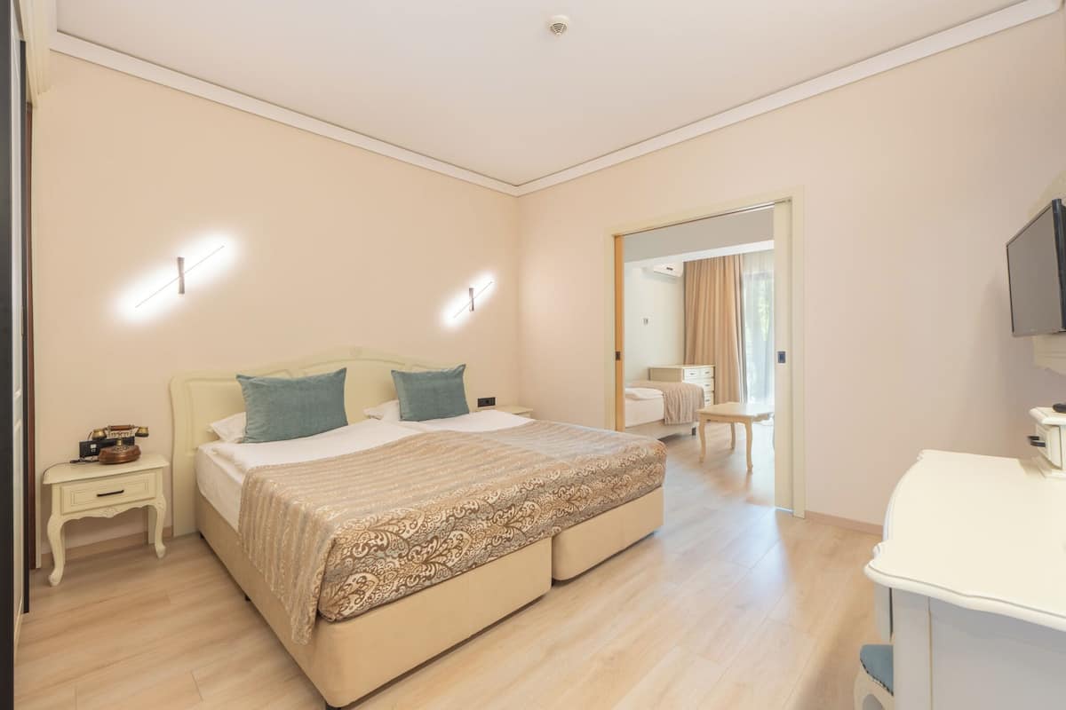 Ein Schlafzimmer mit einem großen Bett, Nachttischen, einem Schreibtisch und einem Fernseher.