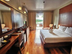 Een hotelkamer met een bed, een bureau met een computer, een stoel, een televisie en een grote spiegel.