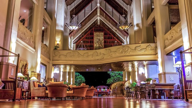 A spacious lobby with high ceilings, ornate woodwork, and a grand staircase.