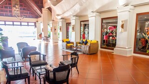 A spacious lobby with a high ceiling, tiled floor, and a seating area with chairs and sofas.
