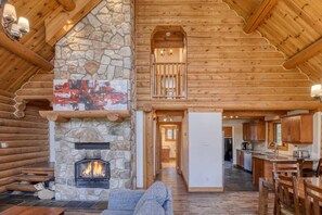 A log cabin interior with a stone fireplace, wooden walls, a dining area, and a kitchen. - Spacious 5-bedroom cabin in peaceful Labelle with AC (Labelle)