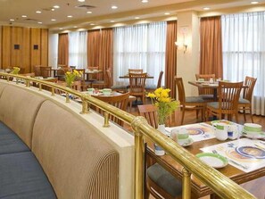 Uma área de refeições de hotel com várias mesas, cadeiras e um longo banco.