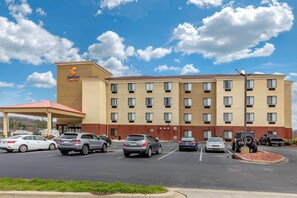 Ein Comfort Suites Hotel mit Parkplatz, mehreren Autos und blauem Himmel.