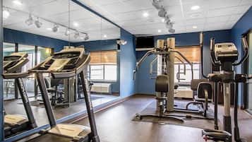 Un gimnasio con cintas de correr, máquinas de pesas y espejos.