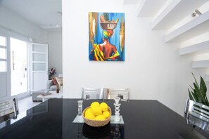 Ein stilvoller Essbereich mit einem schwarzen Tisch, klarem Glas und einem Korb voller Zitronen.