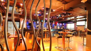 A bar area with stools, a counter, and a seating area with tables and chairs.