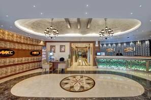 Eine Hotelhalle mit einer Rezeption, einem großen Dekorationsmuster auf dem Boden und einer Kronleuchter.