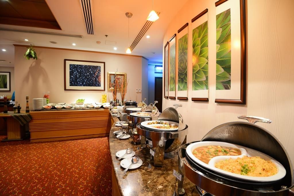 A buffet setup with various dishes, a framed artwork on the wall, and a patterned carpet.
