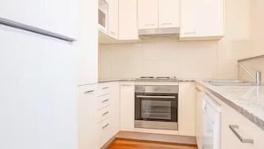 A kitchen with white cabinets, a stainless steel oven, and a wooden floor. - Loftberg Villas (Muswellbrook)